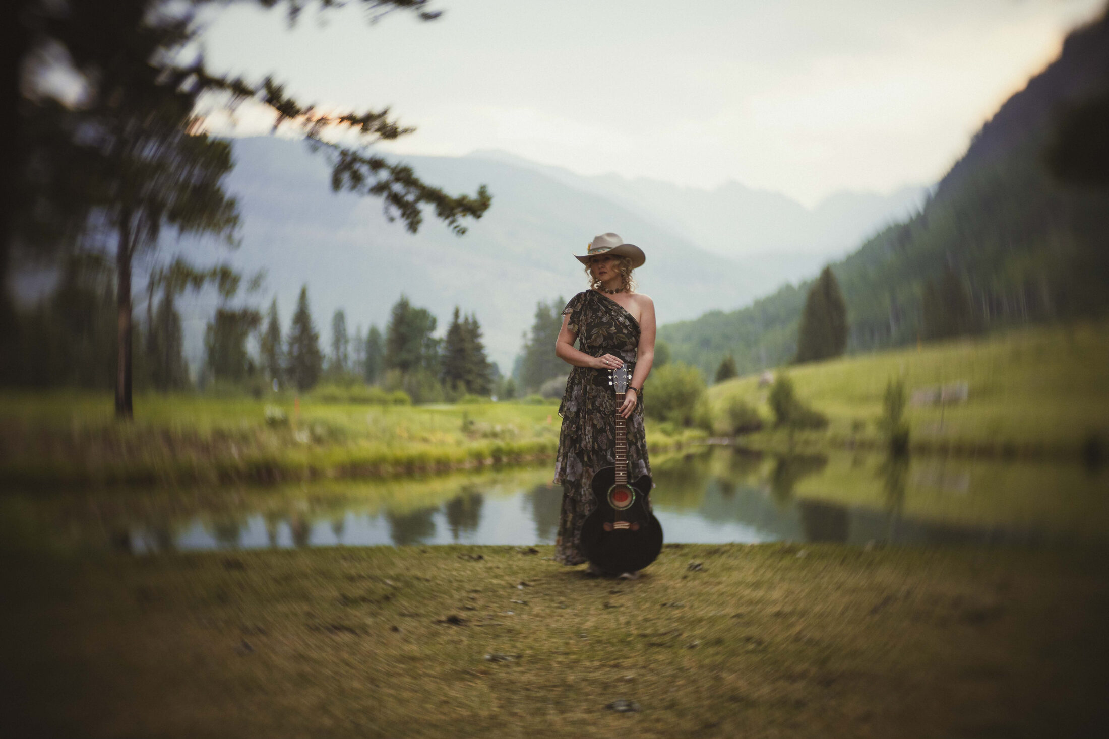 Clar with guitar beside water in the Vail Valley